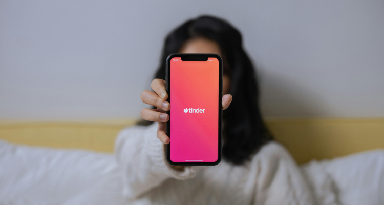 Woman holding a phone with the Tinder app, illustrating buyer psychology in digital interactions.